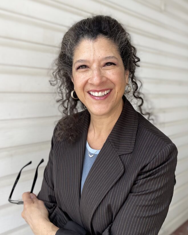 Rachel Hartman, owner of Pivot Office Services — smiling in a pinstripe blazer, glasses in hand